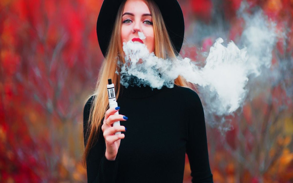 Young woman in black clothing and blonde hair is smoking a thc vape pen.